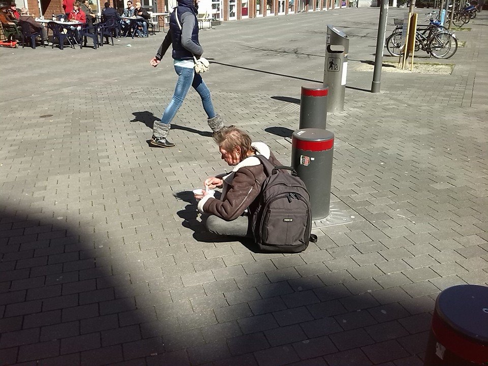 Obdachlosigkeit ist kein Campingurlaub Das Bild zeigt einen Obdachlosen, der in einer Fußgängerzone auf dem Boden sitzt